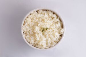 Bowl of cooked long grain white rice garnished with herbs