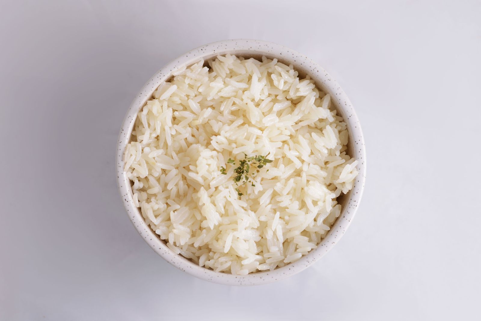 Bowl of cooked long grain white rice garnished with herbs